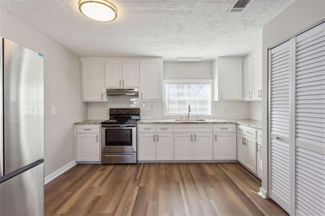 5119 NE Worsham St, Covington, GA 30014 - kitchen with stainless steel appliances, under cabinet range hood, dark wood finished floors, white cabinets, and tasteful backsplash