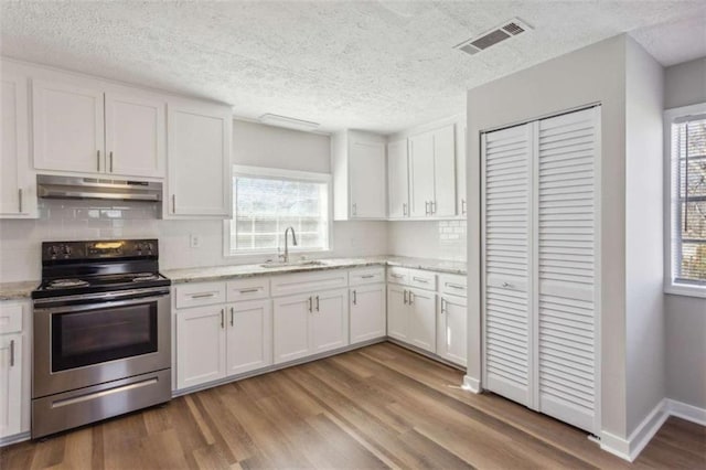 5119 NE Worsham St, Covington, GA 30014 - kitchen with electric stove, under cabinet range hood, light wood-style floors, backsplash, and white cabinets