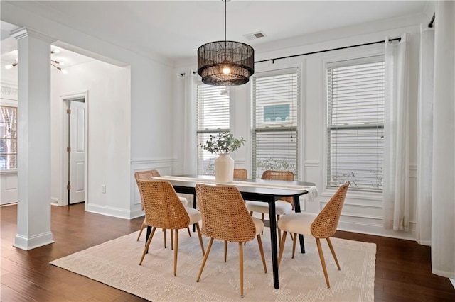 dining space featuring dark hardwood / wood-style floors, decorative columns, and an inviting chandelier