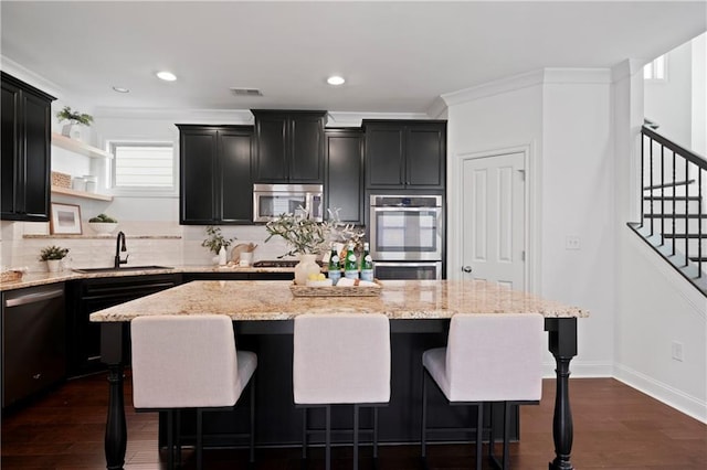 kitchen featuring appliances with stainless steel finishes, dark hardwood / wood-style flooring, sink, a kitchen island, and a breakfast bar area