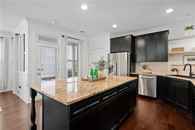 kitchen with light stone countertops, appliances with stainless steel finishes, dark hardwood / wood-style flooring, sink, and a center island