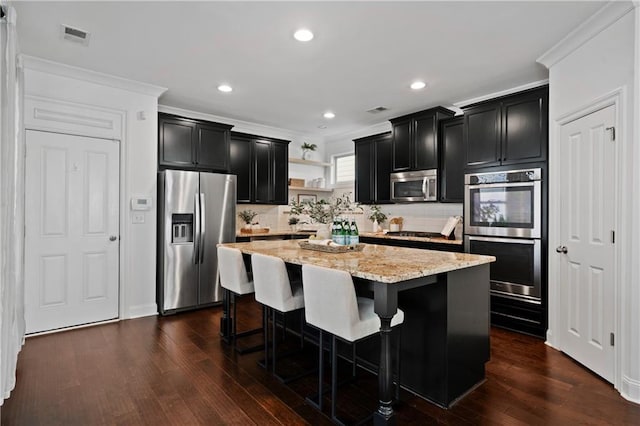 kitchen featuring a center island, a kitchen breakfast bar, dark hardwood / wood-style floors, light stone countertops, and stainless steel appliances