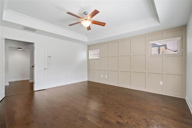 spare room with dark hardwood / wood-style floors, a raised ceiling, ceiling fan, and a healthy amount of sunlight