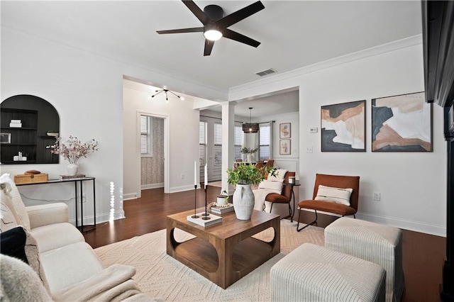 living room featuring ceiling fan, ornamental molding, dark wood-type flooring, and ornate columns