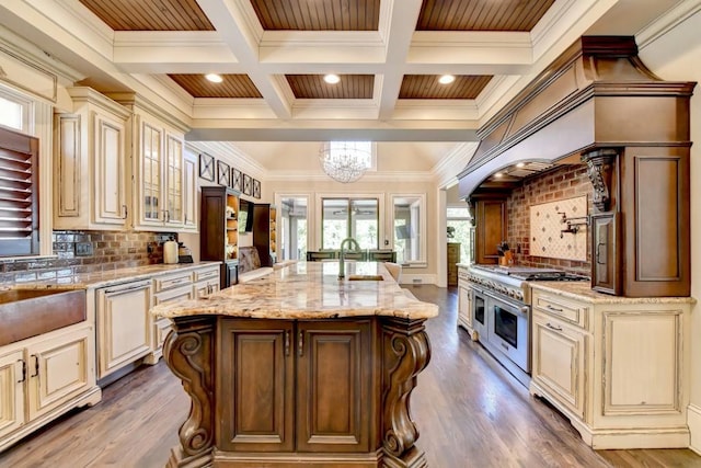 kitchen with light stone counters, a sink, cream cabinetry, and ornamental molding