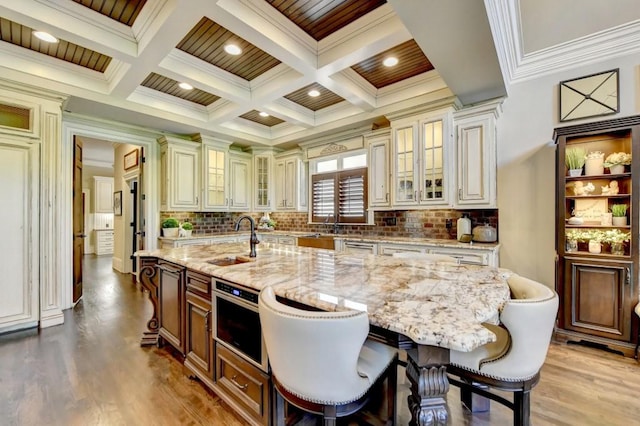 kitchen featuring cream cabinets, beam ceiling, crown molding, and a sink