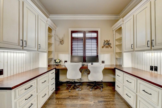 office space with built in study area, crown molding, a wainscoted wall, and dark wood-style floors