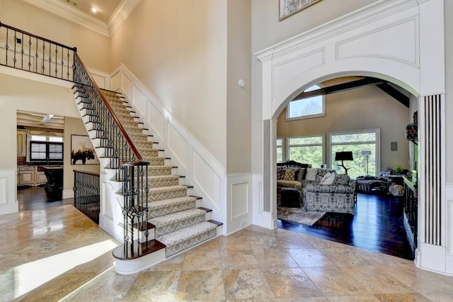 foyer entrance with arched walkways, a high ceiling, and a decorative wall