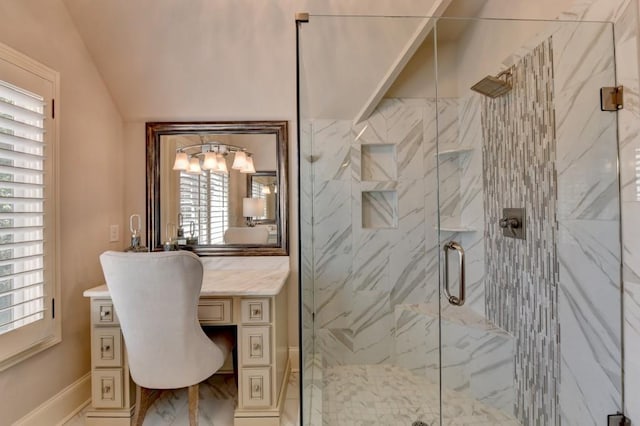 bathroom with a marble finish shower, lofted ceiling, and vanity