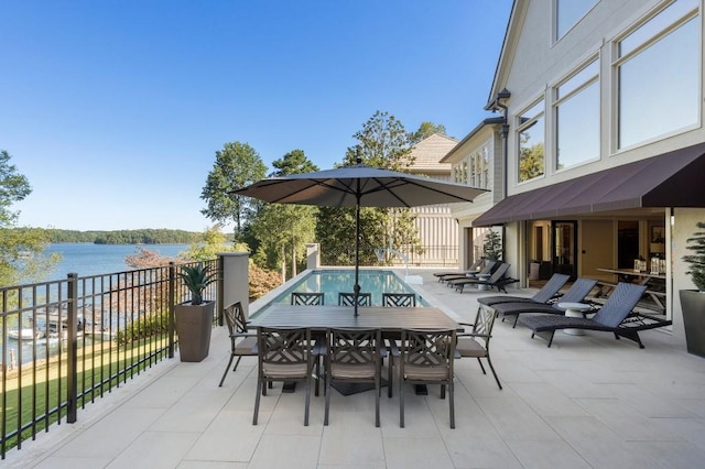 view of patio with a water view, fence, and outdoor dining area