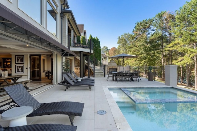 view of pool with a pool with connected hot tub, a patio area, stairway, fence, and outdoor dining space