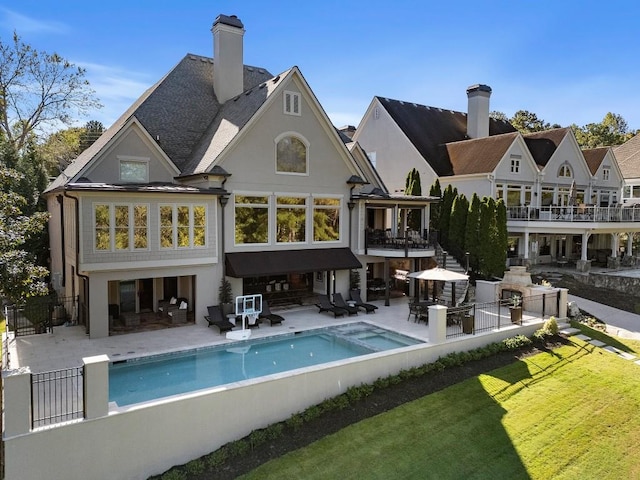 back of property with a fenced backyard, stucco siding, a yard, and a patio area