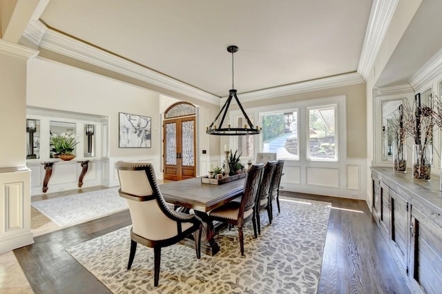dining space with wainscoting, dark wood-style floors, ornamental molding, and a decorative wall