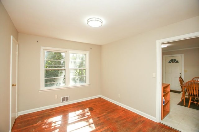 unfurnished room with visible vents, baseboards, and wood finished floors