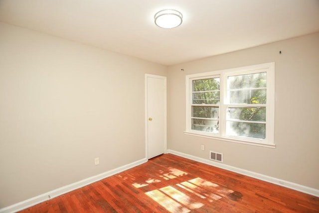 spare room with visible vents, baseboards, and wood finished floors