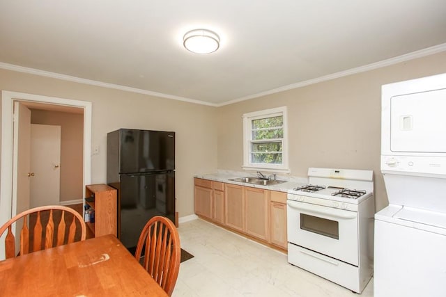 kitchen featuring stacked washer and clothes dryer, a sink, white gas range oven, freestanding refrigerator, and light countertops