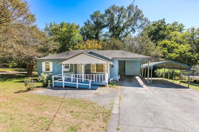 bungalow-style house featuring a detached carport, a porch, a front yard, and aphalt driveway