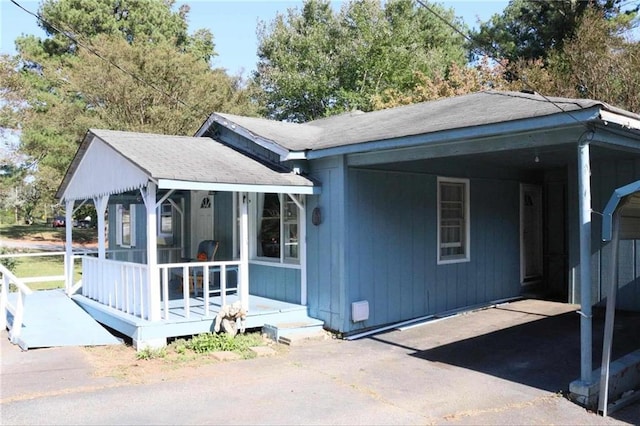 view of front facade with an attached carport, roof with shingles, and driveway