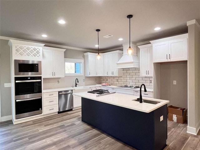 kitchen featuring tasteful backsplash, white cabinets, light wood-style flooring, custom exhaust hood, and stainless steel appliances