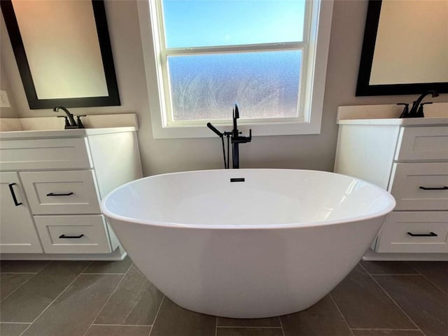 bathroom with a freestanding bath, a sink, tile patterned flooring, and two vanities