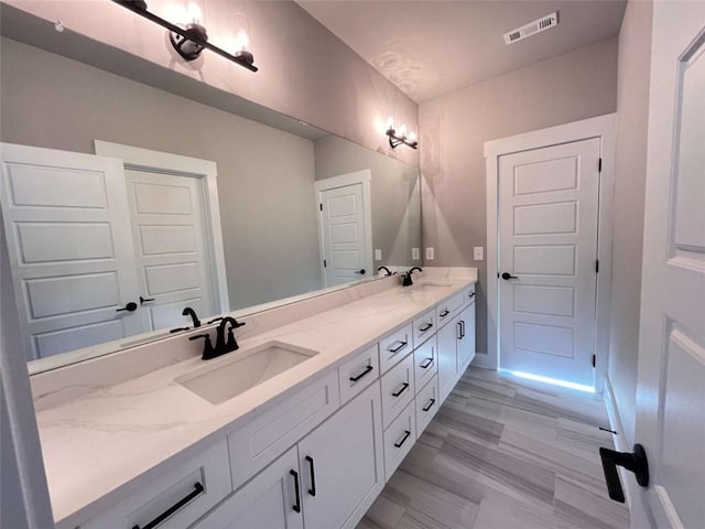 bathroom featuring visible vents, a sink, baseboards, and double vanity