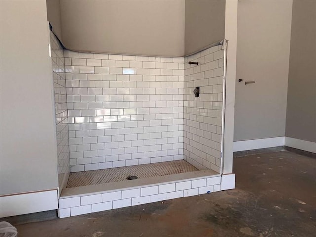 bathroom with unfinished concrete floors, a stall shower, and baseboards