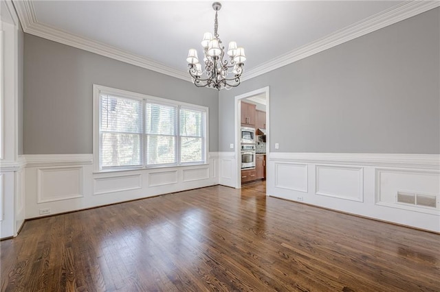 unfurnished dining area with visible vents, dark wood-type flooring, a wainscoted wall, ornamental molding, and a notable chandelier