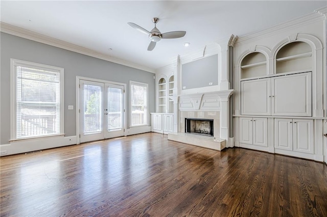 unfurnished living room featuring a premium fireplace, dark wood-style flooring, built in shelves, and ornamental molding