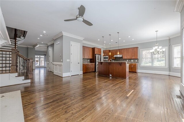 unfurnished living room with stairs, ornamental molding, dark wood-style flooring, and ceiling fan with notable chandelier