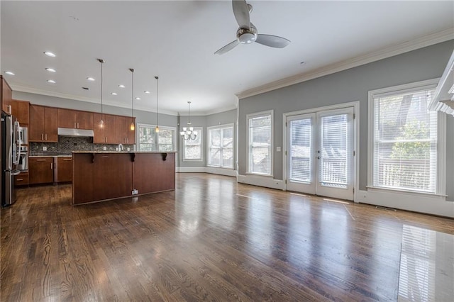 kitchen with dark wood-type flooring, under cabinet range hood, a kitchen breakfast bar, open floor plan, and decorative backsplash