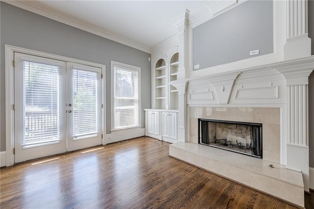 unfurnished living room with built in features, wood finished floors, a high end fireplace, french doors, and crown molding