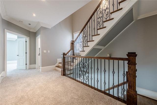 stairs with baseboards, ornamental molding, and carpet flooring