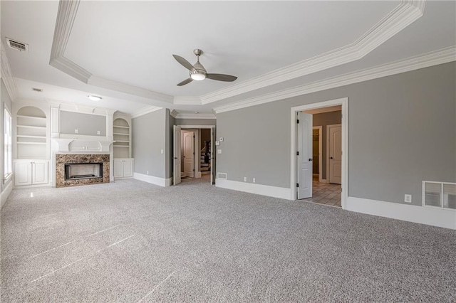 unfurnished living room featuring a raised ceiling, a fireplace, visible vents, and light carpet