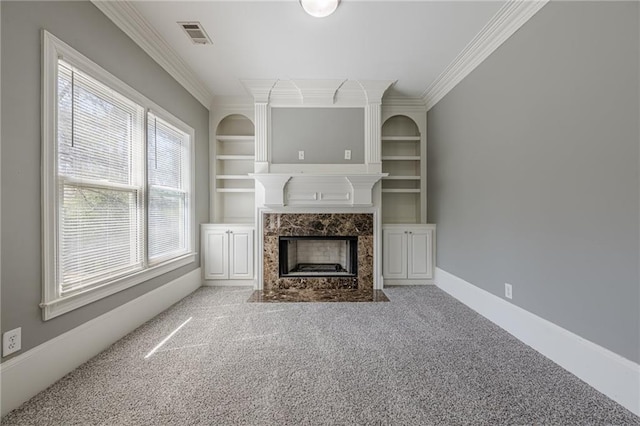 unfurnished living room with a high end fireplace, built in shelves, baseboards, and ornamental molding