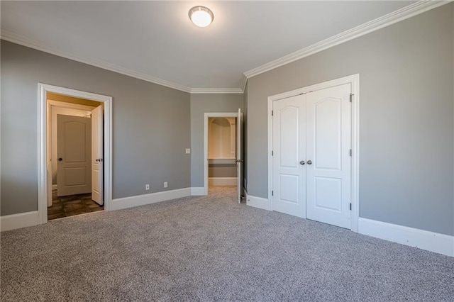 unfurnished bedroom featuring crown molding, carpet, baseboards, and a closet