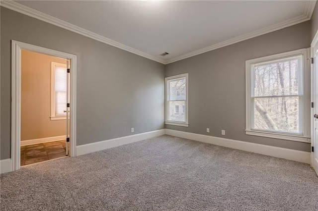 empty room with crown molding, carpet, visible vents, and baseboards