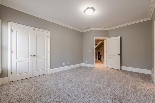 unfurnished bedroom with carpet, baseboards, a closet, and ornamental molding