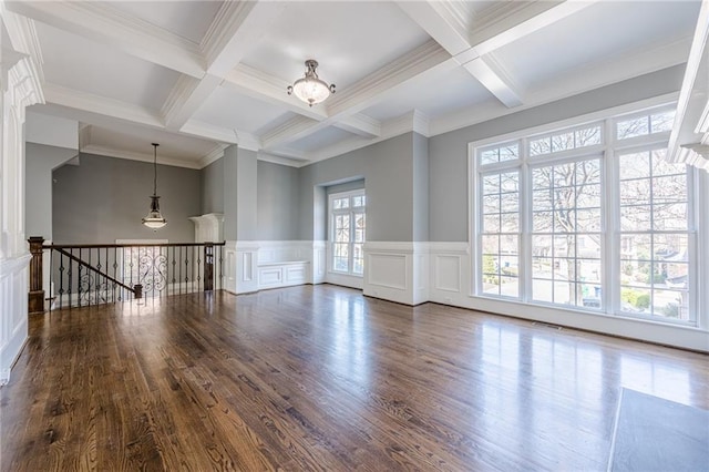 spare room with beamed ceiling, coffered ceiling, wood finished floors, and wainscoting