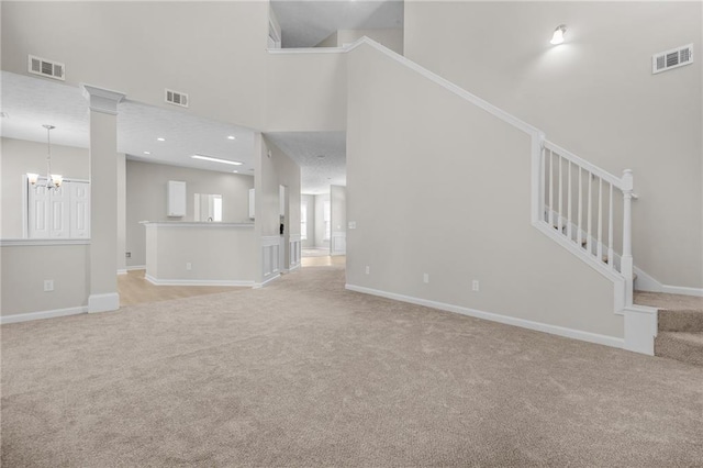 unfurnished living room featuring stairway, visible vents, and light colored carpet