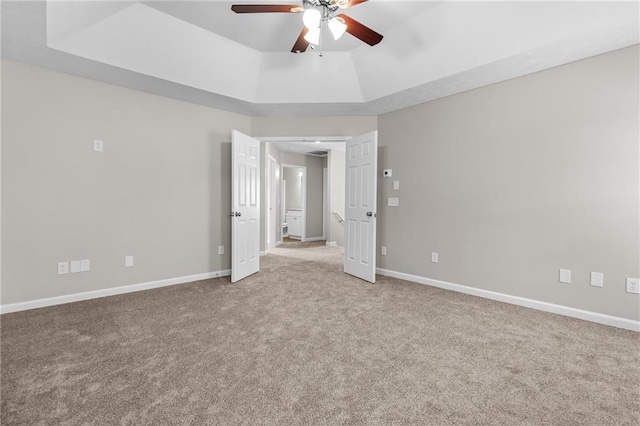 unfurnished bedroom with ceiling fan, carpet flooring, a raised ceiling, and baseboards