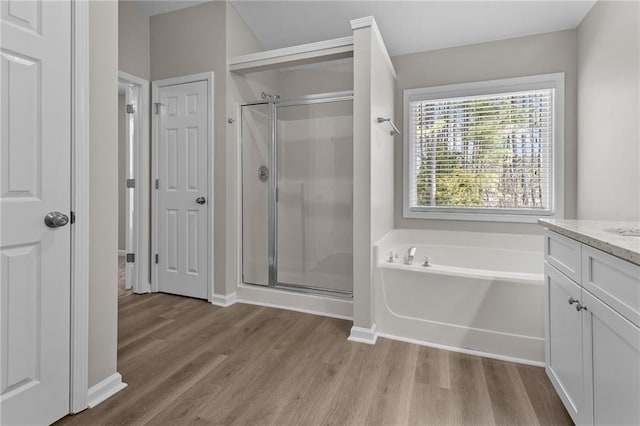 bathroom with a shower stall, wood finished floors, a bath, and vanity