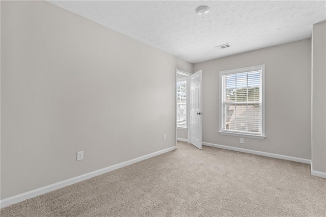 carpeted spare room with a textured ceiling, visible vents, and baseboards