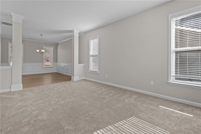 spare room featuring a chandelier, carpet floors, ornamental molding, and baseboards