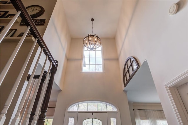 entryway featuring an inviting chandelier and a towering ceiling