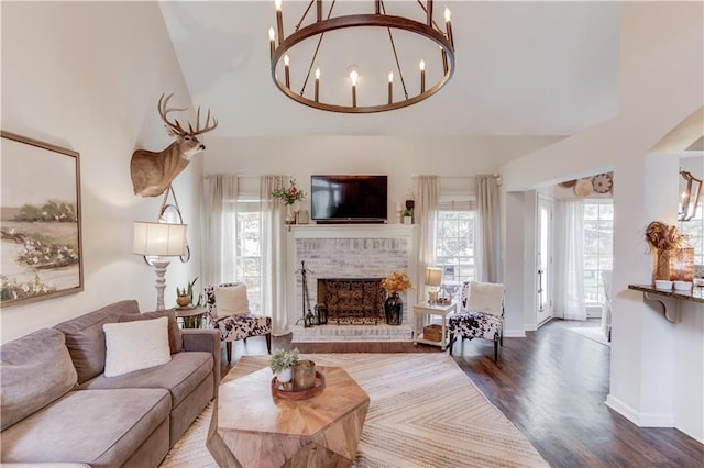 living room with a towering ceiling, hardwood / wood-style floors, a notable chandelier, and a fireplace