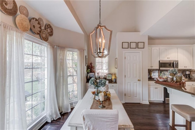 dining area featuring high vaulted ceiling, dark wood-type flooring, and a chandelier