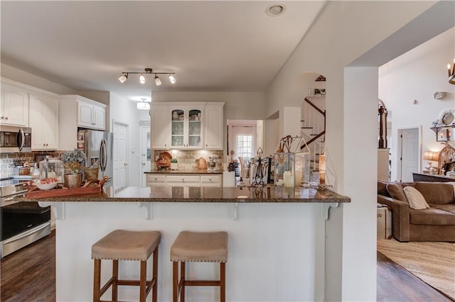 kitchen featuring a breakfast bar area, stainless steel appliances, kitchen peninsula, and white cabinets