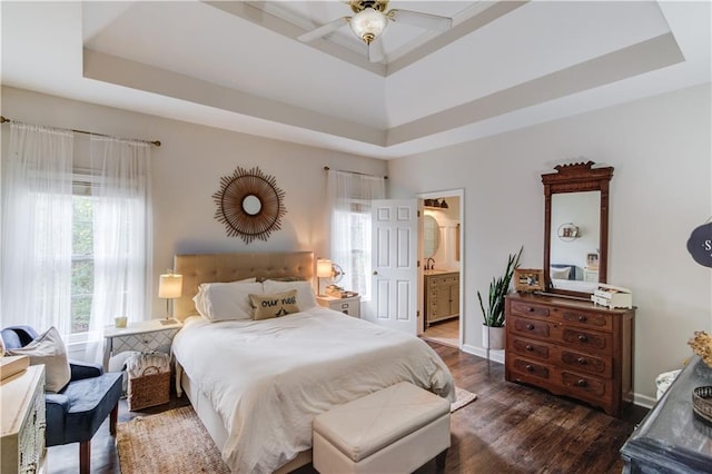 bedroom with ensuite bathroom, dark hardwood / wood-style floors, sink, and a tray ceiling