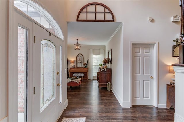 foyer entrance featuring a towering ceiling, dark wood-type flooring, and ornamental molding