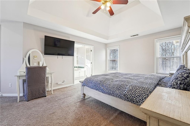 carpeted bedroom featuring ensuite bathroom, a raised ceiling, and ceiling fan